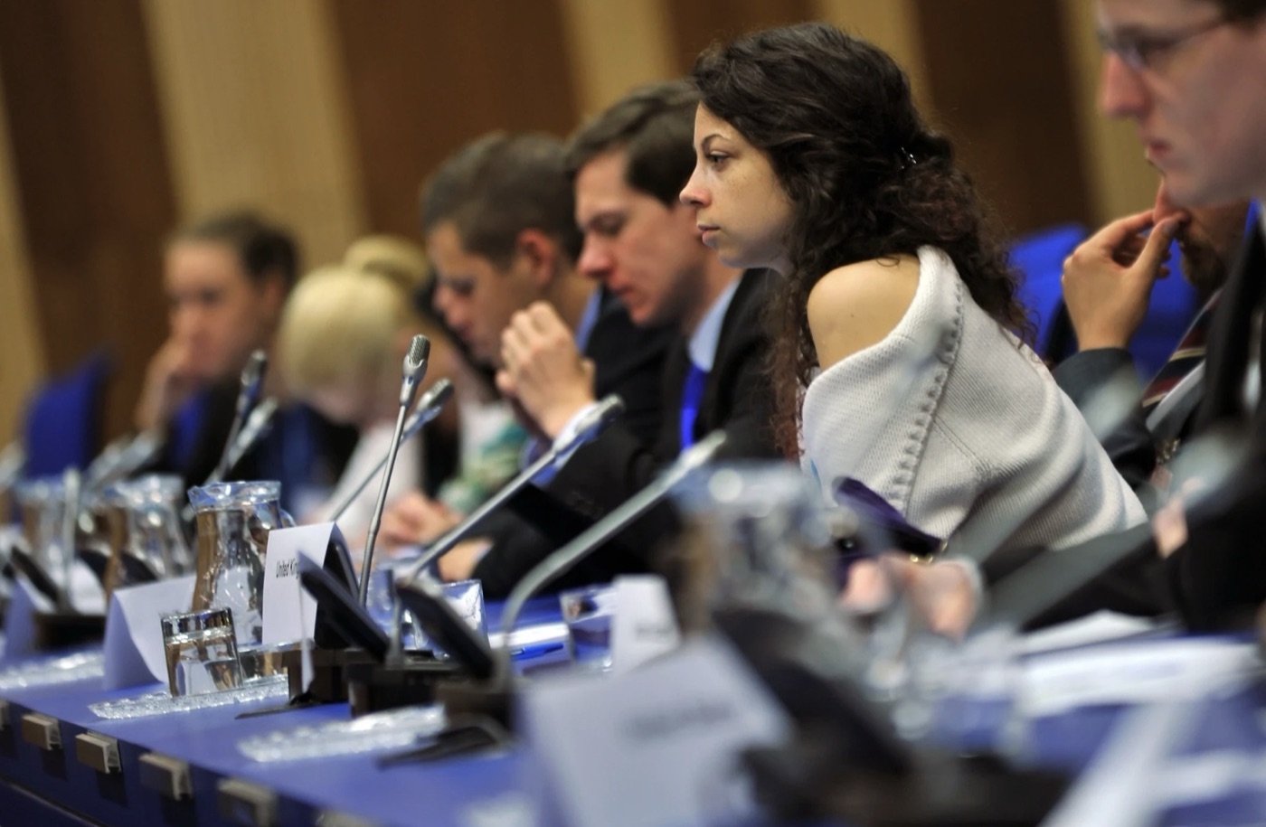Young delegates seated at a conference table with microphones and country placards
